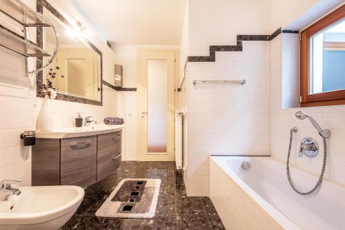 a bathroom with a sink and a tub and a toilet at Apartement Santner in Siusi