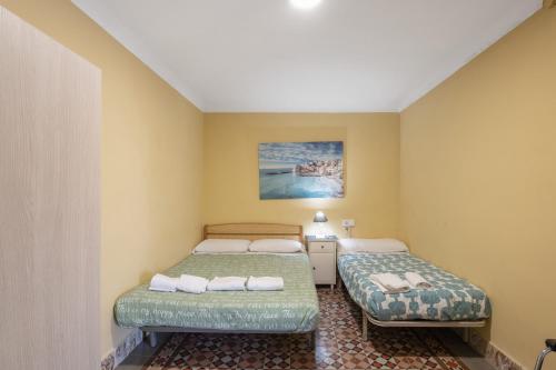 two beds in a room with yellow walls at Masia Cal Vies in Castellví de la Marca