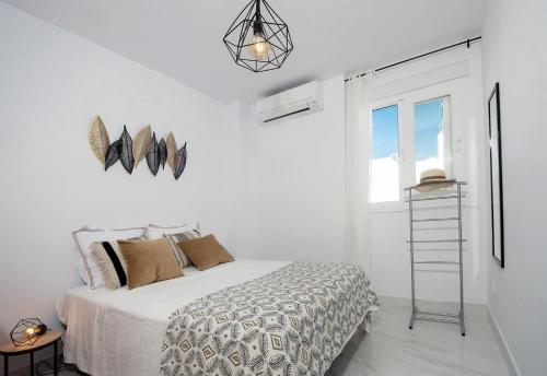 a white bedroom with a bed and a window at Casa Chana in Almuñécar
