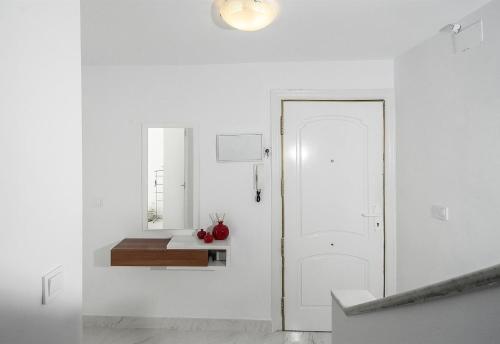 a white hallway with a white door and a mirror at Casa Chana in Almuñécar
