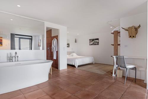 a bathroom with a tub and a bedroom with a bed at Cortijo La Almazara in Ronda