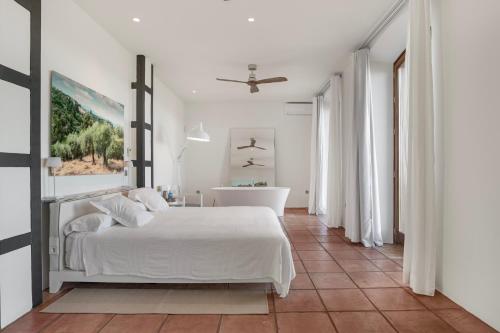 a white bedroom with a bed and a bathroom at Cortijo La Almazara in Ronda