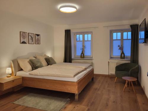 a bedroom with a bed and a chair and windows at Dreimäderlhof Ferienhaus in Karlstetten