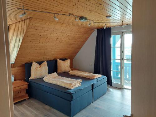 a bedroom with a blue bed with a wooden ceiling at Ferienwohnung Reinbold in Durbach