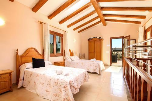 a bedroom with two beds in a room with wooden ceilings at Villa Barraca in Pollença