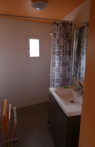 a bathroom with a sink and a mirror and a window at Gîte Chez Claudette in Briord