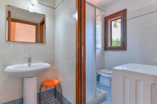 a white bathroom with a sink and a toilet at Il Sarago in Marina di Campo