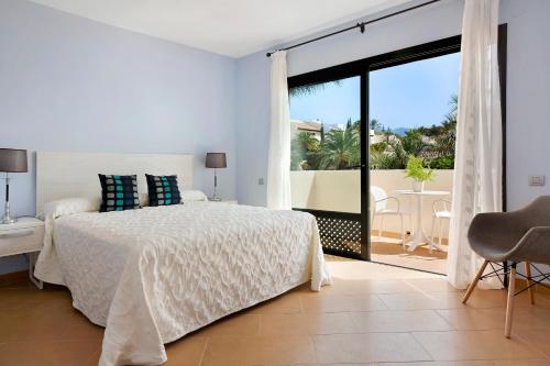 a white bedroom with a bed and a balcony at Villa Pueblo Don Thomas in Playa de Santiago