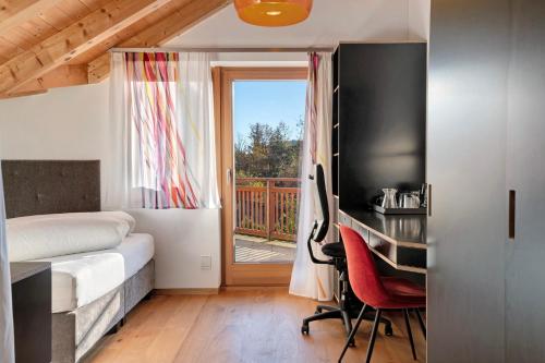 a bedroom with a bed and a desk and a balcony at Residence Skutial Santner Deluxe in Castelrotto