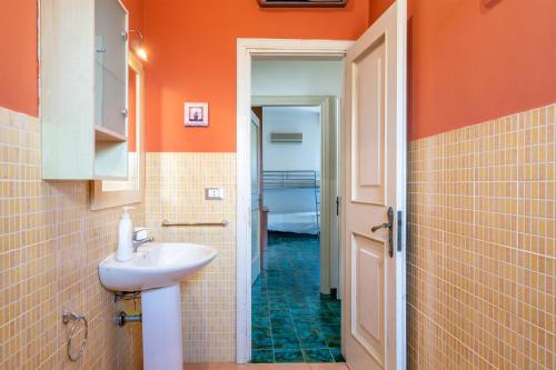 a bathroom with a sink and an orange wall at Bes Beach - Villa con piscina in Fontane Bianche