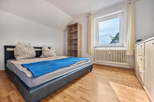 a bedroom with a bed with a blue blanket and a window at Schöner Ith Blick in Salzhemmendorf