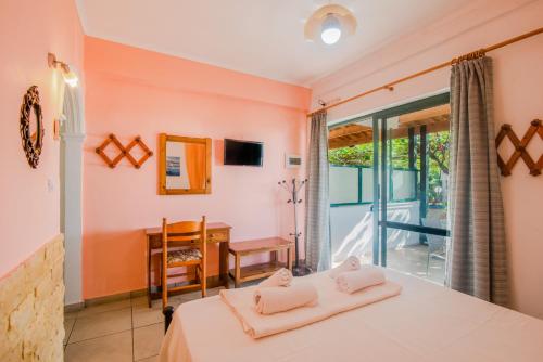 a bedroom with a bed and a desk and a balcony at Family apartment in Corfu