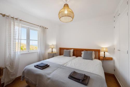 a white bedroom with two beds and a window at Casa da Praia in Praia de Odeceixe