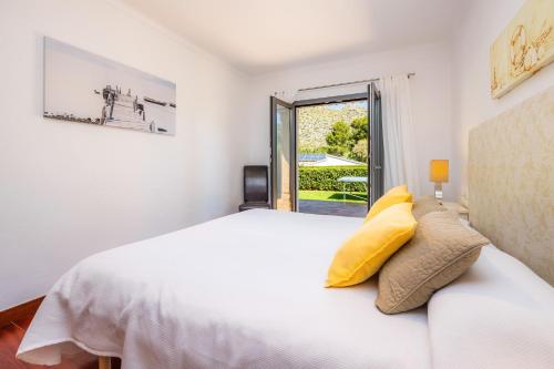 a white bedroom with a bed and a window at Can Domingo in Pollença
