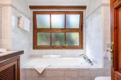 a white bathroom with a tub and a window at Can Domingo in Pollença