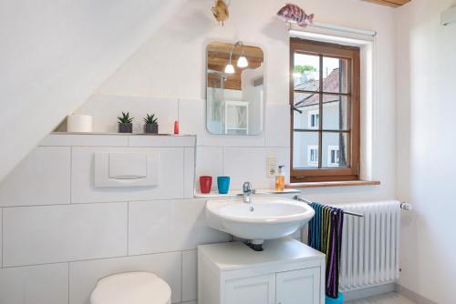 a white bathroom with a sink and a mirror at Ferien im Fachwerk in Bermatingen