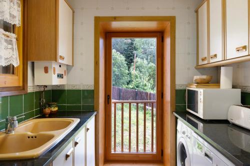 a kitchen with a sink and a door to a balcony at Chalet de montaña con vistas in Prullans