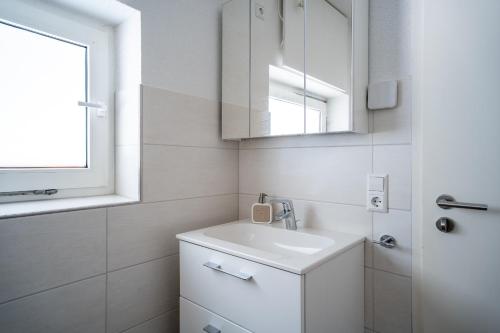 a white bathroom with a sink and a mirror at Ferienwohnung Agnes in Rheinfelden