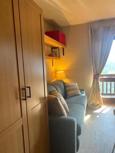 a living room with a blue couch and a window at Ninette, intimità e natura in Sauze di Cesana