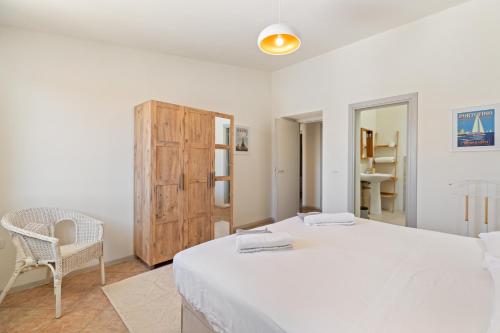 a white bedroom with a bed and a chair at I Tre Nuraghi in Tresnuraghes