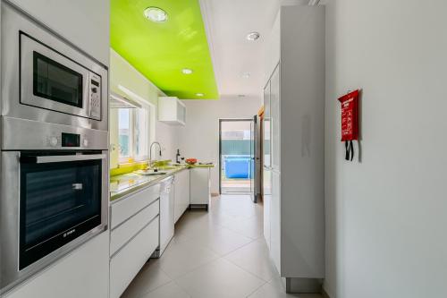 a kitchen with white cabinets and a green ceiling at Casa d' Ana in Sesimbra