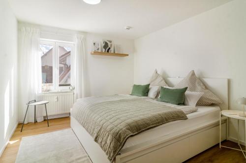 a white bedroom with a large bed with green pillows at Ferienapartment Olivia in Bodman-Ludwigshafen