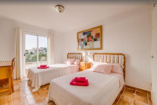 two beds in a room with a window at Algueret in Portopetro
