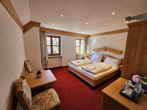 a bedroom with two beds and a table and a chair at Hotel Rusticone Hechendorf in Seefeld