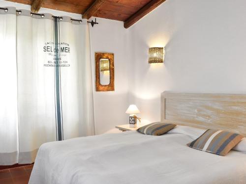 a white bedroom with a bed and a window at Villa Bua in Costa Rei