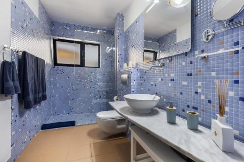 a blue tiled bathroom with a toilet and a sink at Carmina House in Costa Calma