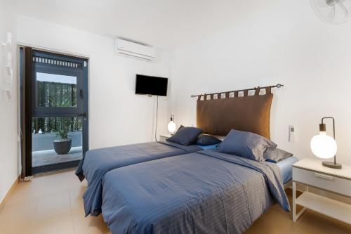 a white bedroom with a blue bed and a window at Carmina House in Costa Calma