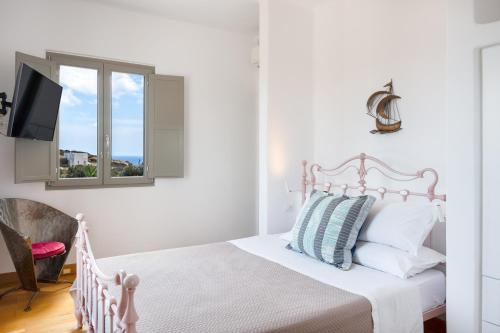 a white bedroom with a bed and a window at Luna Rossa Milos - Moon Kiss in Provatas