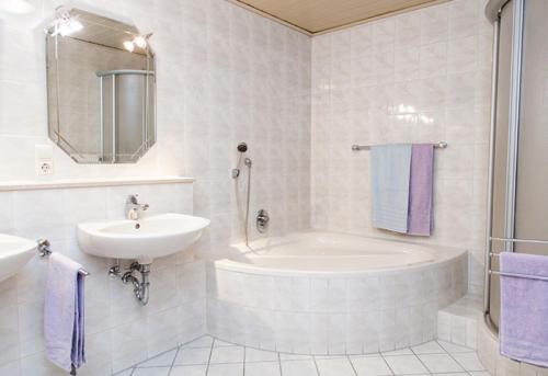 a white bathroom with a sink and a tub and a toilet at Geigerbauernhof in Mühlenbach