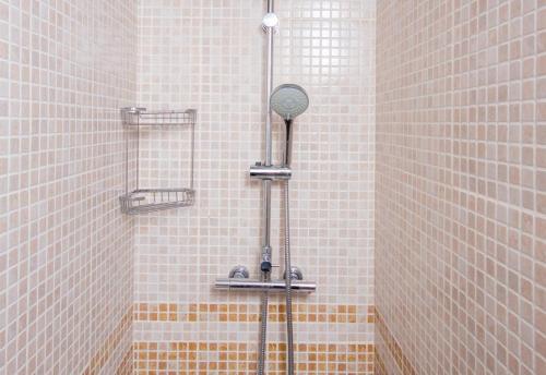 a shower in a bathroom with white tiles at Studio 2 Sea front in Rincón de la Victoria