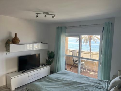 a bedroom with a bed and a television and a balcony at Studio 2 Sea front in Rincón de la Victoria