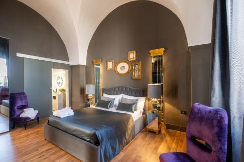a bedroom with a bed and two purple chairs at Maison Boutique At Daniela in San Pietro in Lama
