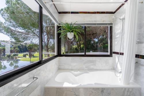 a bathroom with a tub and a large window at Ganso golf in Benalmádena