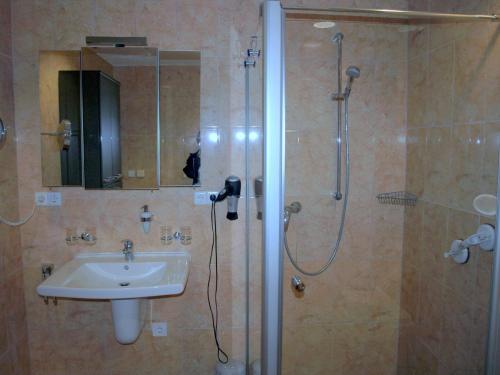 a bathroom with a sink and a shower with a mirror at Ferienwohnung Mengelberg in Markkleeberg