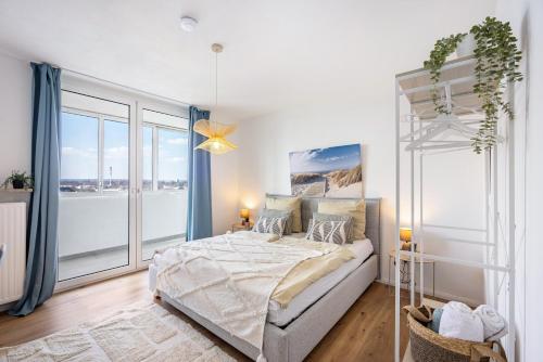 a white bedroom with a bed and a large window at Fewo Sonnenaufgang, Ausblick in Augsburg