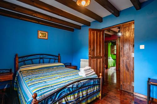 a bedroom with a bed with blue walls at Casa Rural Ricao in Cangas de Onís