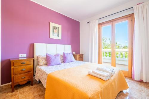 a bedroom with purple walls and a bed and a window at Que Bo in Alcudia