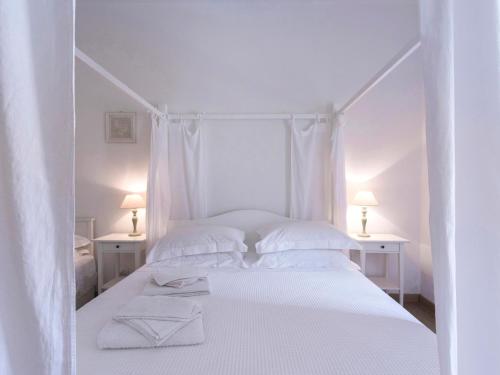 a white bedroom with a white bed with two white tables at Delicious House Michelangelo in Cavaion Veronese
