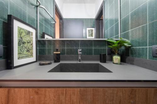 a bathroom with a large sink and green tiles at Lake Como Design Home in Lecco