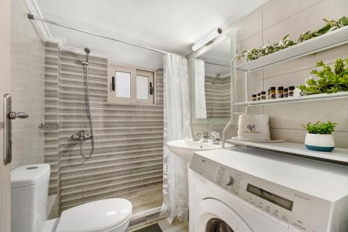 a bathroom with a toilet sink and a washing machine at Evagelia Luxury Apartment 2 in Nikiana