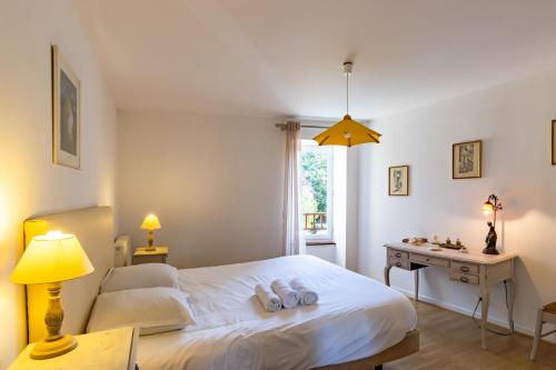 a bedroom with a white bed and a desk at Maison en pierre piscine clim in Varennes