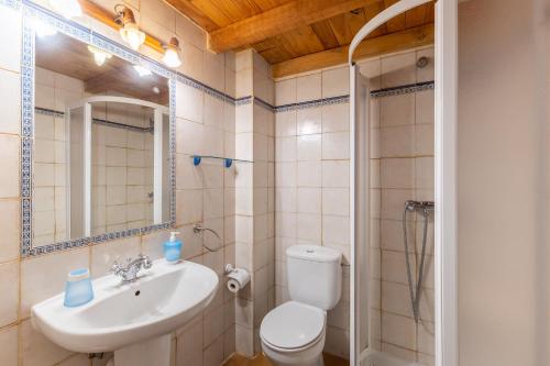 a bathroom with a toilet and a sink and a mirror at La Cárcava in La Serna del Monte