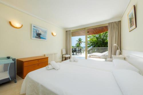 a bedroom with two white beds and a television at Olympo in Port de Pollensa