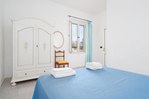 a bedroom with a blue bed and a chair at Villa Sa Mela 28 in Orosei