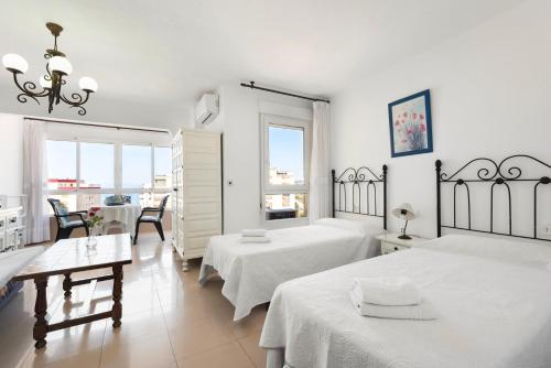 a white room with two beds and a table and chairs at Estudios 79 in Torrox