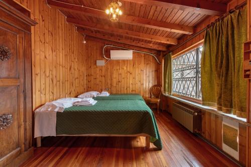 a bedroom with a green bed in a wooden room at Very Elegant Historic Apartment F2 in Gravedona